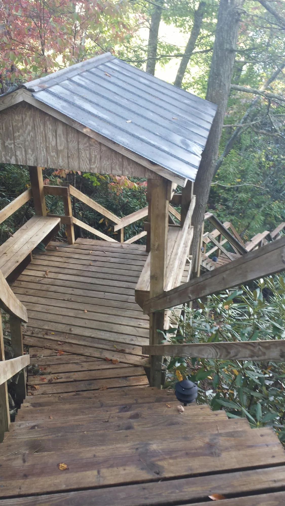 Metal roofed shelter over wooden steps on a wooded walkway — Skylight Repair & Installation work by our crew in Waterville