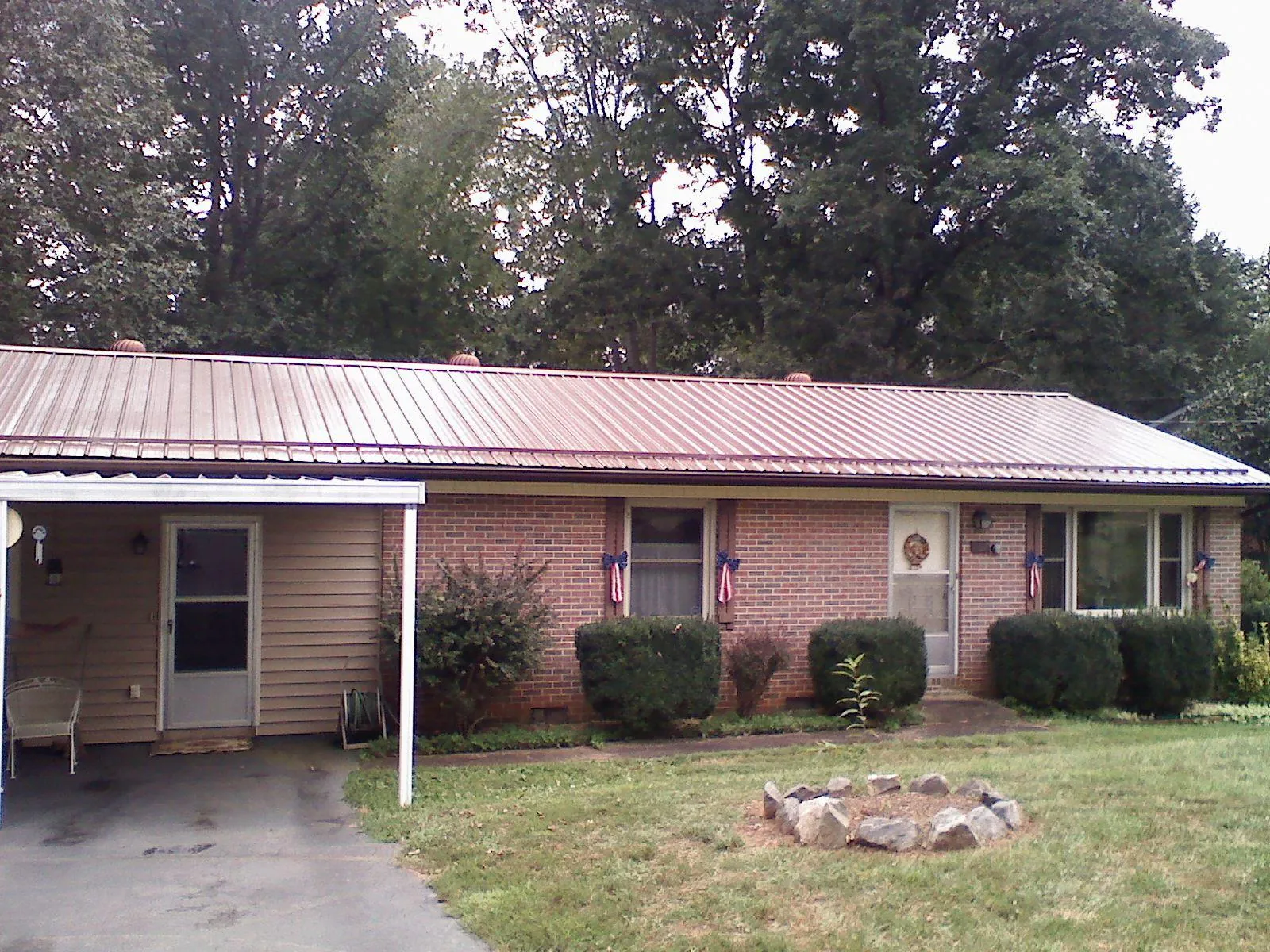 Bronze metal roof and carport on a brick ranch home — Roof Repair work by our crew in Waterville